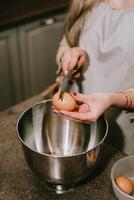 Break an egg into a saucepan. A girl breaks eggs in a bowl to make pastries. The process of baking with your own hands. photo