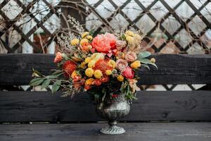 Juicy bright autumn Bridal bouquet, wedding bouquet in boho style, red orange flowers in the composition of the bouquet, a bouquet of flowers stands on a bench in the garden photo