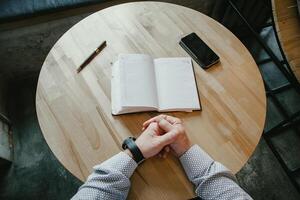 top view men's hands and diary lying on the table, businessman sitting at the table, round table Notepad phone pen man, thinking, concentration, planning photo