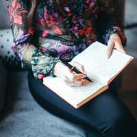 write business ideas in a notebook, a girl sitting in a cafe writes with a pen in a notebook, near the window, transfer thoughts to paper photo
