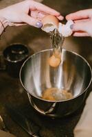 Break an egg into a saucepan. A girl breaks eggs in a bowl to make pastries. The process of baking with your own hands. photo