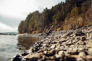 stone lake shore, cold autumn weather on the lake, water, forest on the horizon, autumn landscape photo