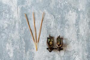 metal door handles in the shape of hands folded in mudra, shot on a textured gray background, close-up, separate object, yoga theme, bronze hue, Indian motif, incense photo