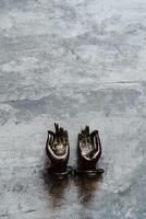 metal door handles in the shape of hands folded in mudra, shot on a textured gray background, close-up, separate object, yoga theme, bronze shade, Indian motif photo
