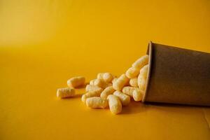 A paper cup filled with popcorn on a yellow background photo