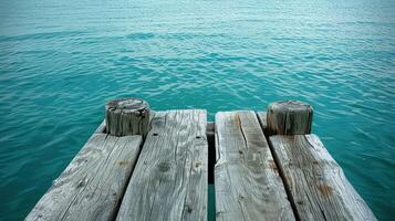 A wooden dock extends over calm turquoise water, creating a sense of tranquility and anticipation. photo