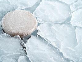 Frozen ice cube on icy surface photo