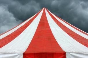 Dramatic storm clouds over a red and white circus tent photo