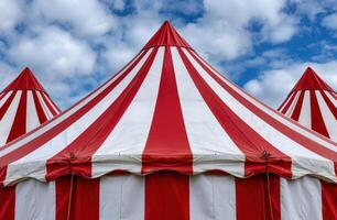 Vibrant red and white circus tent against a cloudy sky photo