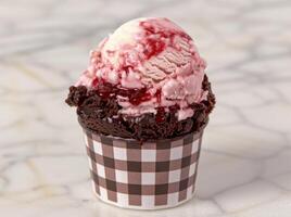 Delicious ice cream sundae with chocolate brownie and raspberry sauce photo