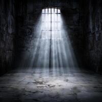 Dramatic light shining through barred window in dark abandoned building photo