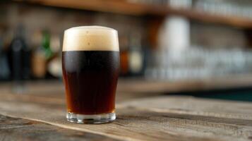 Dark beer in glass on wooden table photo