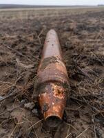 Rusty pipe lying in field photo