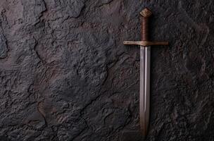 Ornate medieval sword against dark rock background photo