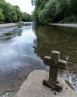 Serene river with moss covered cross photo