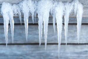 Icicles hanging from a wooden structure photo