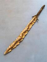 Ornate golden sword on gray background photo