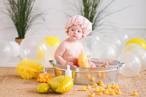 Bath time for baby, child sitting in a basin with rubber ducks photo