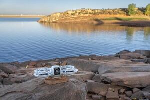 Fort Collins, CO, USA - October 1, 2024 - DJI Neo mini drone on a rocky lake shore, It offers a creative and fun alternative to a selfie stick or tripod. photo