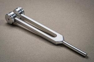 Metal weighted tuning fork used for tuning musical instruments, sound therapy, chakra healing or relaxation. photo