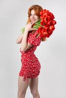 Young happy woman with a bouquet of red lulips. Portrait of a red-haired lady in the studio in front of a white background. photo