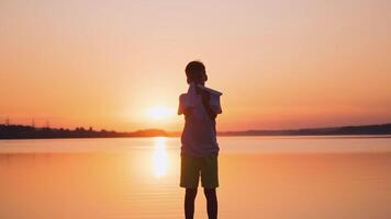 Boy standing with paper planes near the river. Child playing with origami planes in slow motion on the evening river background. video
