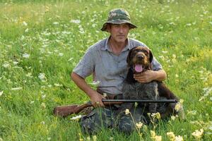 Hunter man in camouflage with a gun during the hunt in search of wild birds or game. photo