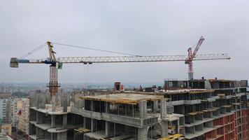 Process of construction high-rise building. Labor workers on a big construction site on the background of working crane in the city. Slow motion. Camera moves top down. video