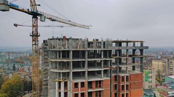 New construction site in the city. Two big cranes constructing the urban building. Construction of high-rise building on the city background. Aerial view. Round motion of camera. video