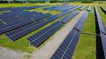 Ecological power station outdoors. Flying over the rows of blue solar panels on the field in summer. New source of electricity. Drone view. video