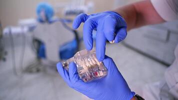 Jaw model in hands. Dentist showing on a jaw model how to put teeth where necessary. Medic in blue gloves. Close-up. video