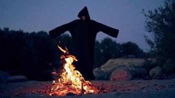 The wicked witch performs a ritual near a bonfire in the night. Mysticism of Halloween video