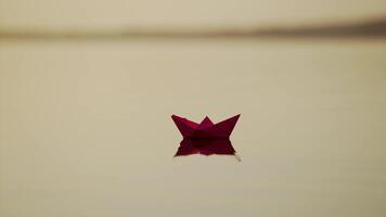 Red Paper Ship in the river. Origami Paper Boat is Sailing in the lake. Beautiful Waves Ripple Background. Unusual Travel Concept. Filtered . video