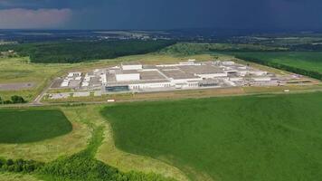 Aerial view on the large territory of industrial structure on the natural landscape in summer. Panoramic view of green fields and manufacturing buildings outdoors. Camera moves right. video