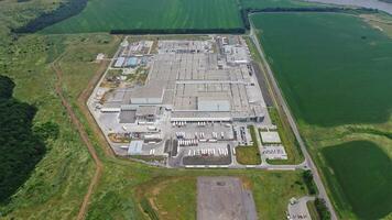 Aerial view of manufacturing area surrounded by green fields. Top view of industrial complex with parking place on natural background. video