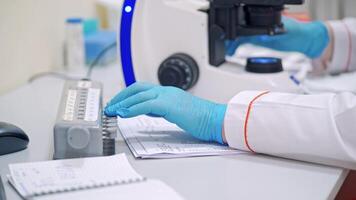 Hands in blue gloves of medical worker. Laboratory scientist works with microscope on thetable. Close-up. video