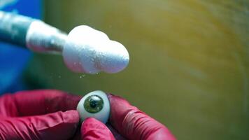 Polishing the eye prosthesis. Hands in pink gloves holding artificial eye at special tool for cleaning. Close-up. video
