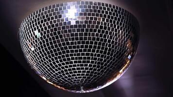 Turning mirror disco ball against dark background. Joy, dancing or party concepts. Spinning mirror disco ball on the ceiling. Close-up. video
