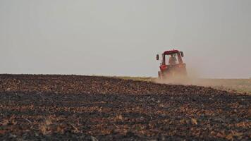 Brown field background and a tractor plowing the soil. Tractor cultivating the field, preparing land for sowing in the farmland. video