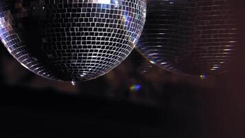 Mirror ball reflect rays of colored lights. Colorful reflective disco mirror ball with glinting highlights spinning slowly on a blurry background in disco club. The light show at night. video