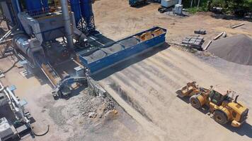 View from above on asphalt factory. Excavator working outdoors. Modern machine transports sand or crushed stones in its bucket. video