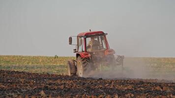 Back view of a tractor plowing the soil. Agricultural machinery preparing land for further works on the field. Process of cultivation the ground. video