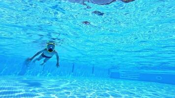 Underwater camera shoots a of a boy inside the pool. Little boy diving with mask underwater in swimming pool. video