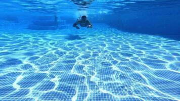 Man swimming under water in the pool. Underwater view of a male swimmer floating in transparent water to the camera. video