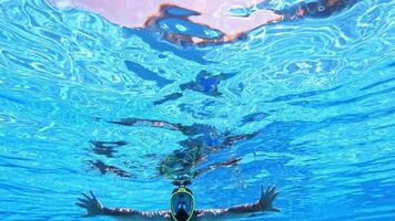 Underwater background of a swimming pool. A man in yellow mask swimming inside the clear blue water of a pool. video