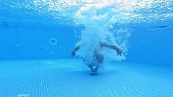 Man jumps under water in the pool. Underwater view on a man diving into water and swimming inside the swimming pool. video