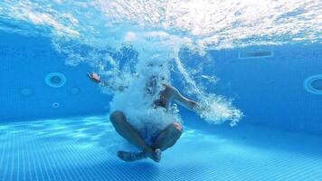 Man jumps into clear water of a pool in yoga pose. Underwater camera shooting a of a man jumping into water. Male shows gesture yes with thumbs underwater. video