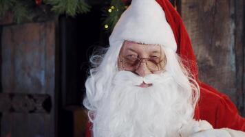 Portrait of Santa blinking his eyes in eyeglasses. Santa Claus with white beard looking at camera and making eye wink indoors. Close-up face of father Frost. video
