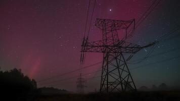 Beautiful aurora lights dance across the night sky, illuminating towering power lines in a tranquil countryside setting. The stunning display creates a breathtaking atmosphere. video