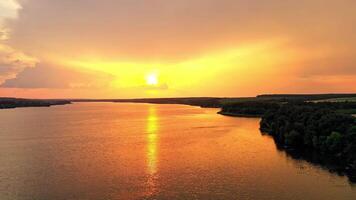 Beautiful orange sunset over the calm river. Natural landscape of green forest and river in the evening. Aerial view. Camera moves left. video